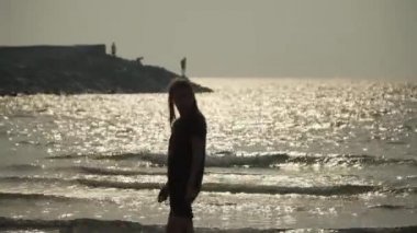 young white girl looks at the sunset over the sea