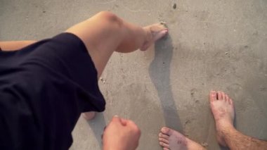 a young couple stands barefoot on the sand 