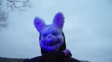 scary evil maniac in a rabbit mask looks at the camera and prepares to kill