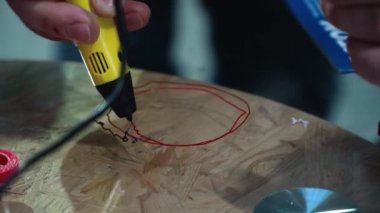 young white man draws 3d with a pen.