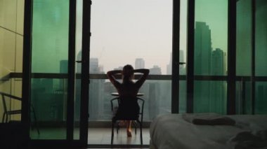 A girl sits on the balcony. Apartment on a very high floor in Dubai