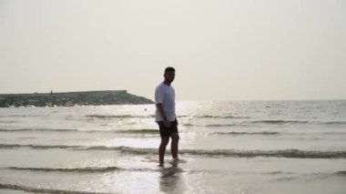 a young guy walks on the water against the backdrop of the sunset
