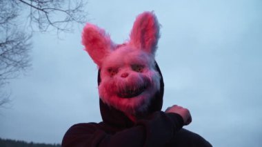 scary evil maniac in a rabbit mask looks at the camera and prepares to kill