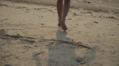 a young white girl walks barefoot on the sand and enters the sea