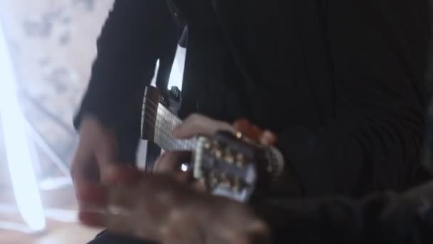 Hombre con una sudadera negra toca la guitarra acústica — Vídeos de Stock