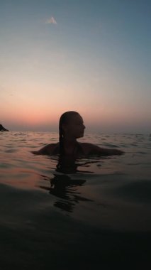 Suda duruyor, ellerini kaldırıyor.