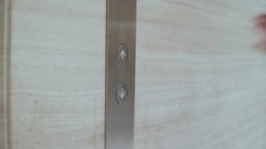 Bir kadının eli asansör çağrı düğmesine basar.