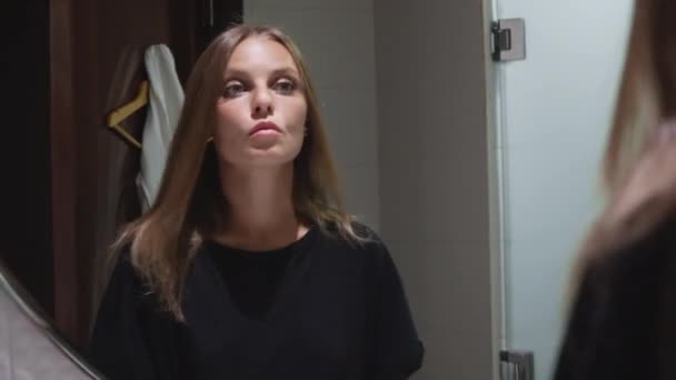 Chica se mira en el espejo en el baño — Vídeo de stock