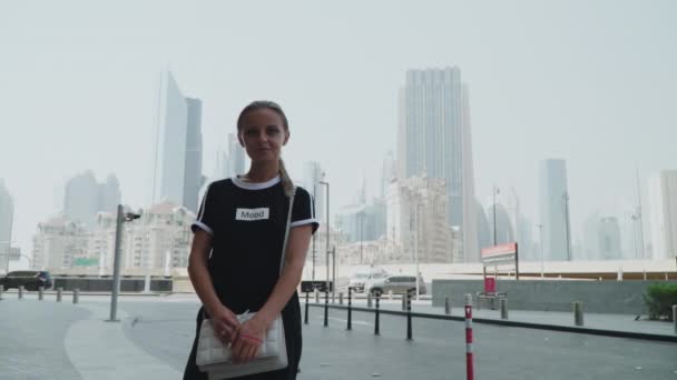 Дівчина стоїть в літньому місті — стокове відео