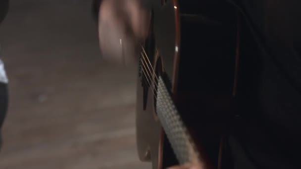 Egy fekete pulóveres férfi akusztikus gitáron játszik. — Stock videók