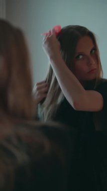 Kız aynanın önünde saçını tarıyor.