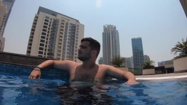 Facet siedzi w basenie na dachu w Dubaju — Wideo stockowe