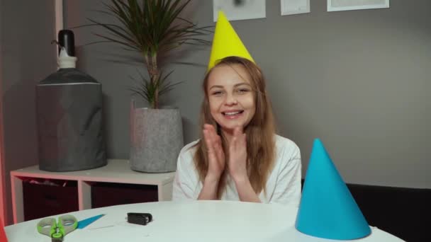 Chica se sienta en una gorra festiva y sonríe. mujer aplaude alegremente — Vídeo de stock