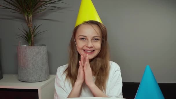 소녀는 축제 모자를 쓰고 미소를 짓습니다. 즐거운 마음으로 박수를 치는 여자 — 비디오
