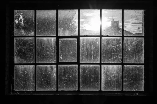 Terk edilmiş fabrikanın kirli penceresinden içeri güneş giriyor.