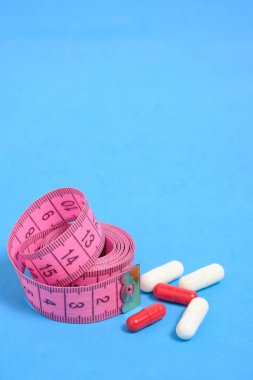 Mavi arkaplan, konsept kilo verme sporları ve spor konsepti üzerindeki bant ve vitamin haplarının ölçümü