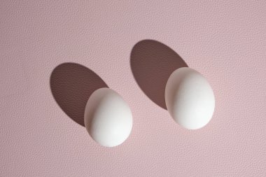Sert ışıkta pembe arka planda iki beyaz yumurta