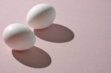 Sert ışıkta pembe arka planda iki beyaz yumurta