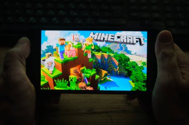 Kostanay, Kazakistan, Kasım 04, 2021 Bir adam popüler Minecraft oyununun ekran koruyucusuyla cep telefonu tutuyor.