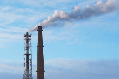 Mavi gökyüzüne karşı iki dumanlı endüstriyel boru