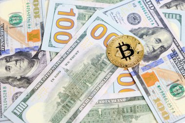 Yüz dolarlık banknotlar ve bir bitcoin.