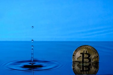 Düşen yağmur damlalarından su sıçrat ve mavi gökyüzüne karşı suya bitcoin para at.
