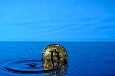 Düşen yağmur damlalarından su sıçrat ve mavi gökyüzüne karşı suya bitcoin para at.