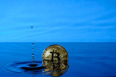Düşen yağmur damlalarından su sıçrat ve mavi gökyüzüne karşı suya bitcoin para at.
