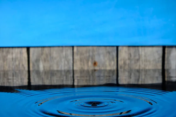 背景に雨滴から水に円やスプラッシュ古いフェンスと青い空 — ストック写真