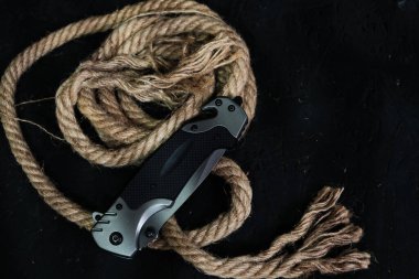 Hayatta kalmak için taktik katlama bıçağı, aktif yaşam tarzı ve eğlence, halat arka planda ve karanlık arka planda