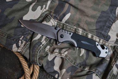 Hayatta kalmak için taktik katlama bıçağı ve kamuflaj için askeri giysiler.