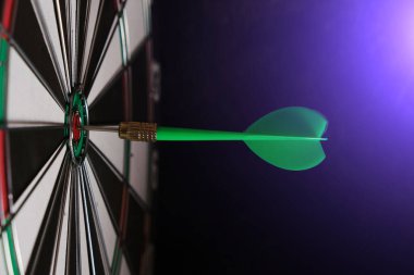 Ortasında yeşil oklar olan bir dart tahtası. Parlak mavi ışık var.