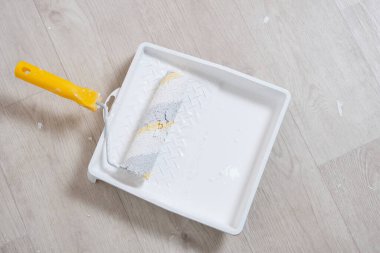 Beyaz boya ve boya silindirli tekerlekli tepsi.