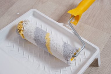 Beyaz boya ve boya silindirli tekerlekli tepsi.