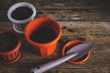 Ahşap arka planda çiçek saksıları ve dekoratif bahçe spatulası.