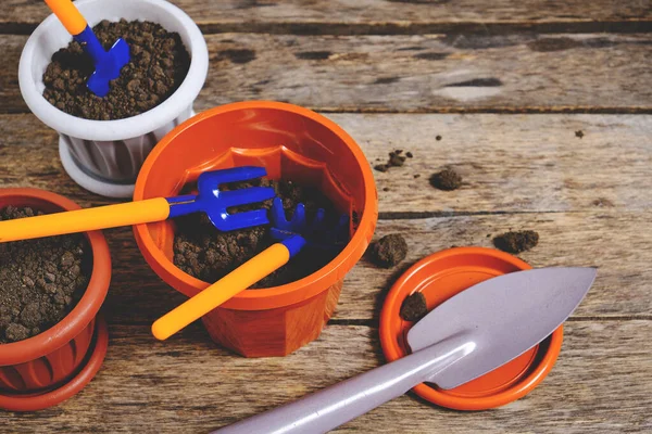 Çiçek saksıları ve dekoratif bahçe aletleri tahtadan bir arka planda kürek, tırmık ve yaba