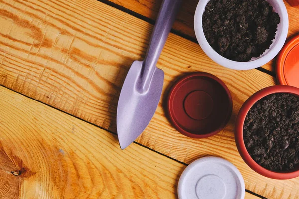 Ahşap arka planda çiçek saksıları ve dekoratif bahçe spatulası.