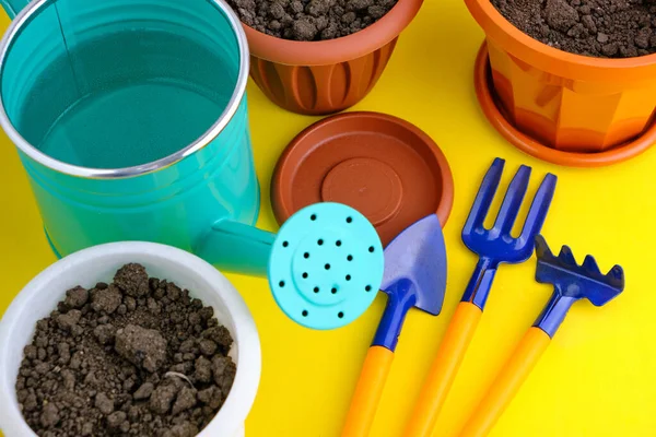 Çiçek saksıları, sulama kutusu ve bahçe aleti parlak sarı arkaplan