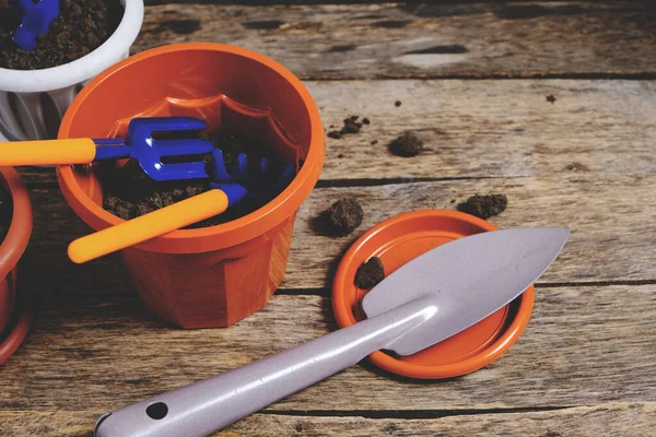 Çiçek saksıları ve dekoratif bahçe aletleri tahtadan bir arka planda kürek, tırmık ve yaba