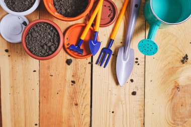 Çiçek saksıları, sulama kabı ve ahşap bir arka planda bahçe aleti