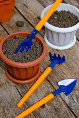 Çiçek saksıları ve dekoratif bahçe aletleri tahtadan bir arka planda kürek, tırmık ve yaba