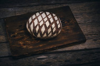 Kırsal ahşap arka planda un serpiştirilmiş somun siyah çavdar ekmeği.