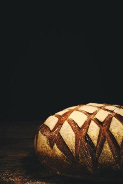 Kırsal ahşap arka planda un serpiştirilmiş somun siyah çavdar ekmeği.