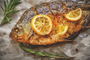 Parşömen kağıdında pişmiş, baharatlı fırında balık, limon ve biberiye.