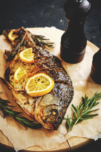 Limonlu ve biberiyeli fırında balık ahşap kesme tahtasının üzerine serilmiştir.