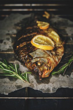 Fırında limon ve biberiye ile pişirilmiş balık. Parşömen kağıdında, ızgaranın üzerine serili.