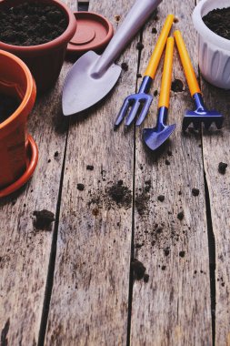 Çiçek saksıları ve dekoratif bahçe aletleri tahtadan bir arka planda kürek, tırmık ve yaba