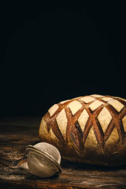 Üzerine un serpiştirilmiş çavdar ekmeği ve koyu arkaplana serpiştirmek için elek.