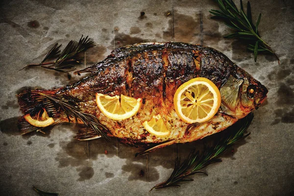 Parşömen kağıdında pişmiş, baharatlı fırında balık, limon ve biberiye.