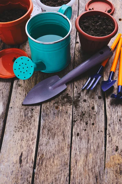 Çiçek saksıları, sulama kabı ve ahşap bir arka planda bahçe aleti